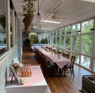The sunroom with large windows overlooking the lagoon at Alexander's Restaurant set up for a private event with pink tablecloths