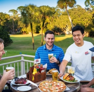 Big Jim's server delivering food to a group of men enjoying a beer on the patio