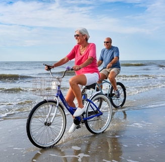 older man and woman riding on bikes on the beach at Palmetto Dunes Oceanfront Resort