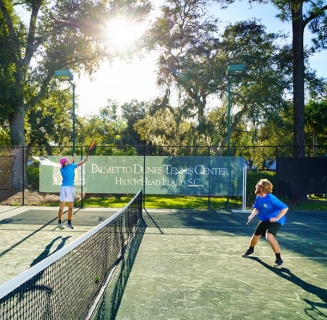 two men actively playing tennis at Palmetto Dunes Tennis Center