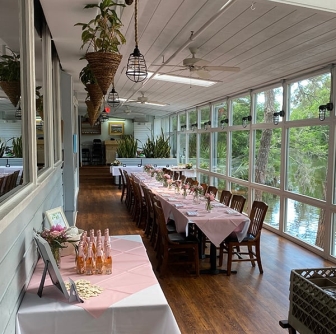The sunroom with large windows overlooking the lagoon at Alexander's Restaurant set up for a private event with pink tablecloths