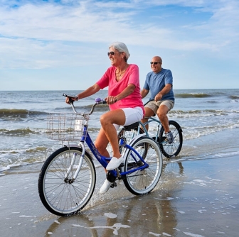 older man and woman riding on bikes on the beach at Palmetto Dunes Oceanfront Resort