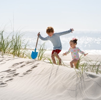  Little boy with shovel and little girl climb the sand dunes at the beach at Palmetto Dunes