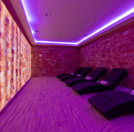 room with purple light and salt walls with a number of large lounge chairs