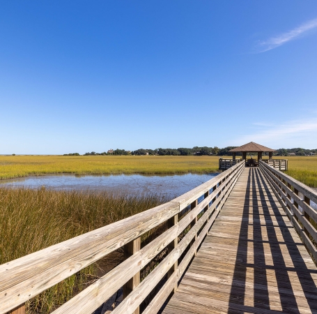 a long dock leading out to a building in a marsh