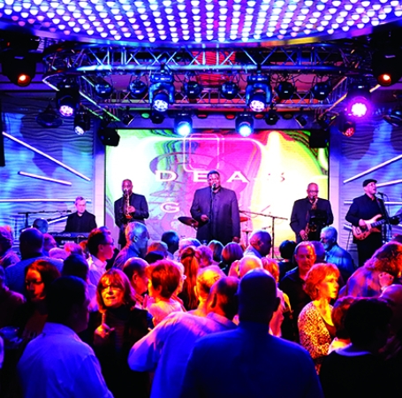 A nightclub packed with people on the dance floor and a band on the stage