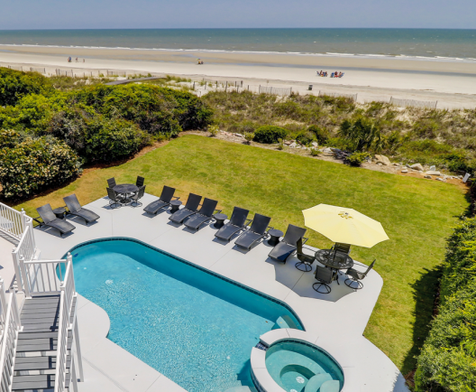 Pool with beach in the background of a vacation home