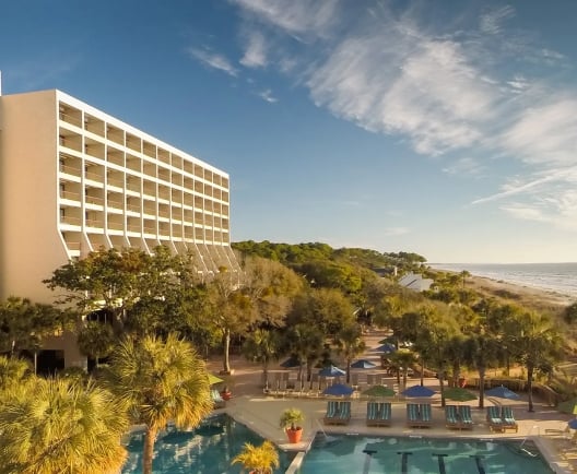 two large buildings with balconies overlooking a pool and the beach