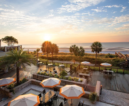 view of the beach from a balcony at sunset overlooking patios with umbrellas