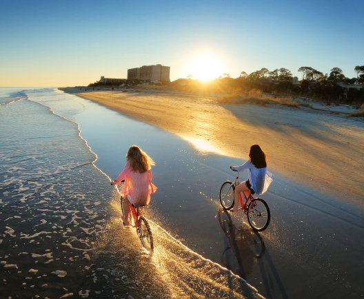 two people biking on the beach