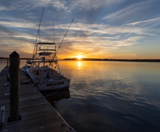 A docked boat with a vibrant sun setting behind it