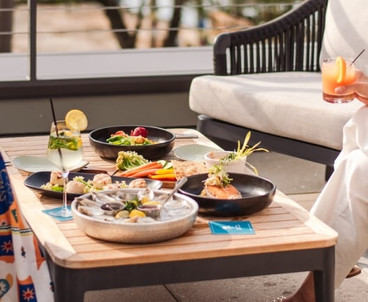 two people sitting on patio enjoying dinner and drinks 
