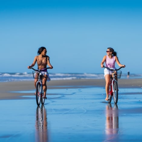 two people biking on the beach