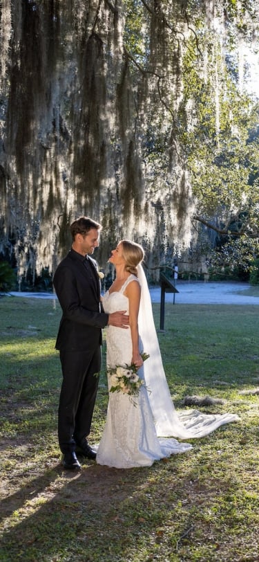 couple in wedding attire standing under spanish moss