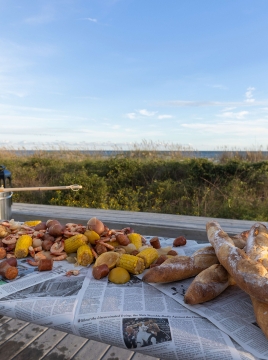 A lowcountry boil set on a large table with white wine and the beach in the distance