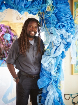 man standing displaying large blue art work 