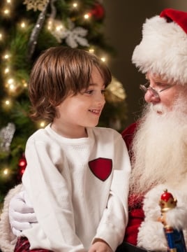 santa with a child in front of a christmas tree