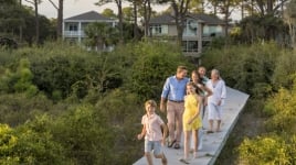 A family of six walk along a boardwalk.