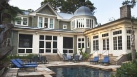 A vacation home with a pool and lounge chairs in the backyard.