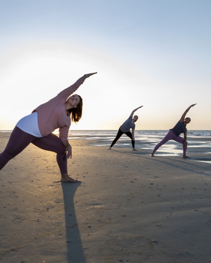 women on the beach doing yoga