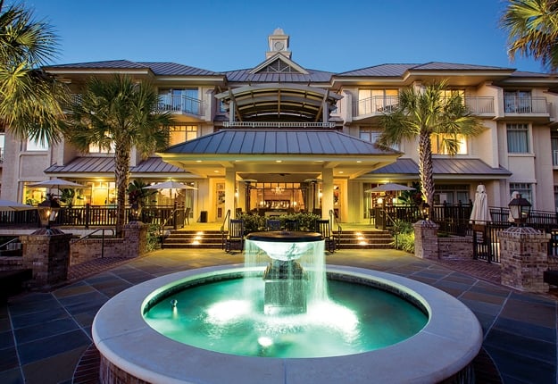 The entrance to a luxury resort at night with a lit up fountain.