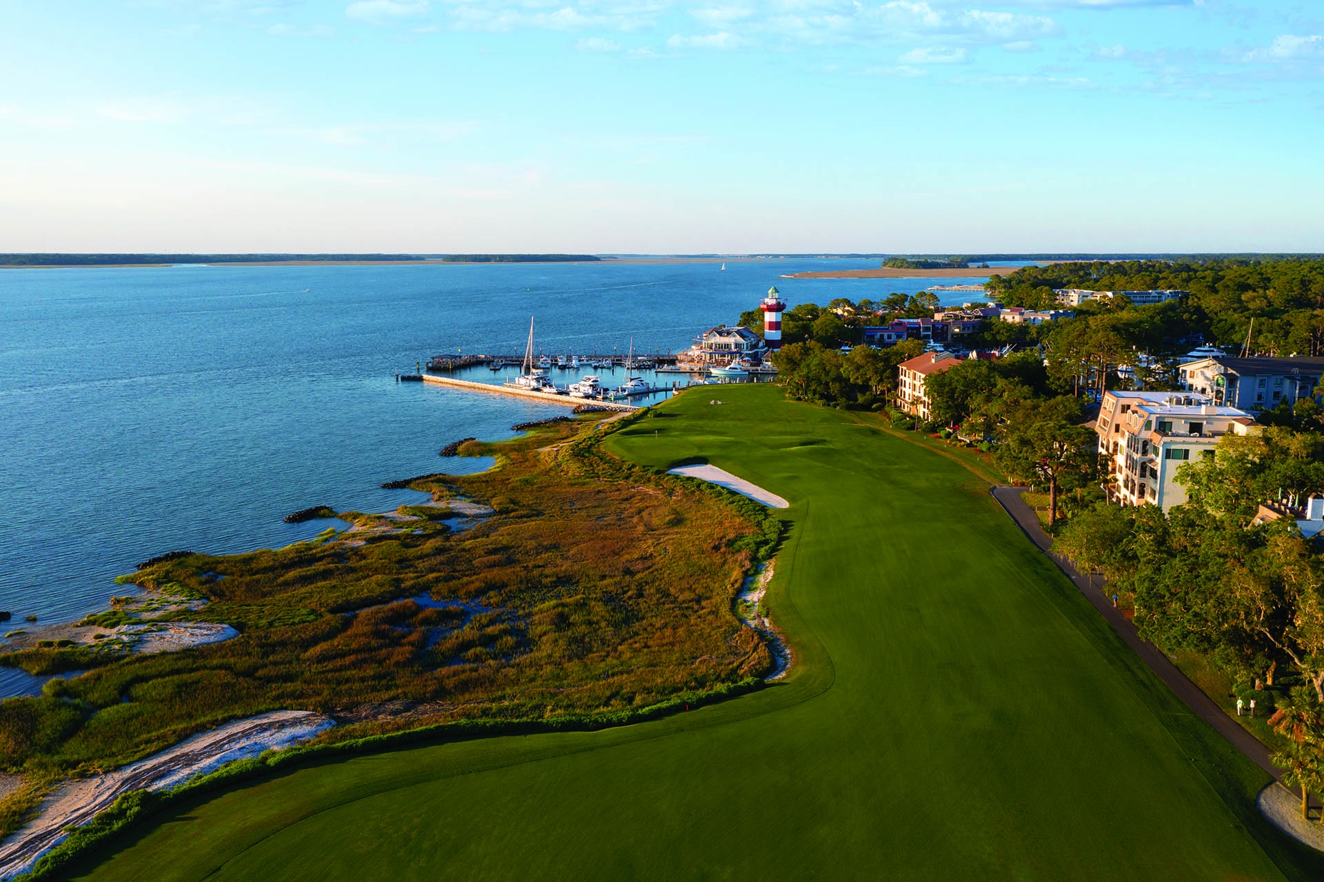aerial view of golf course with water and lighthouse in the background