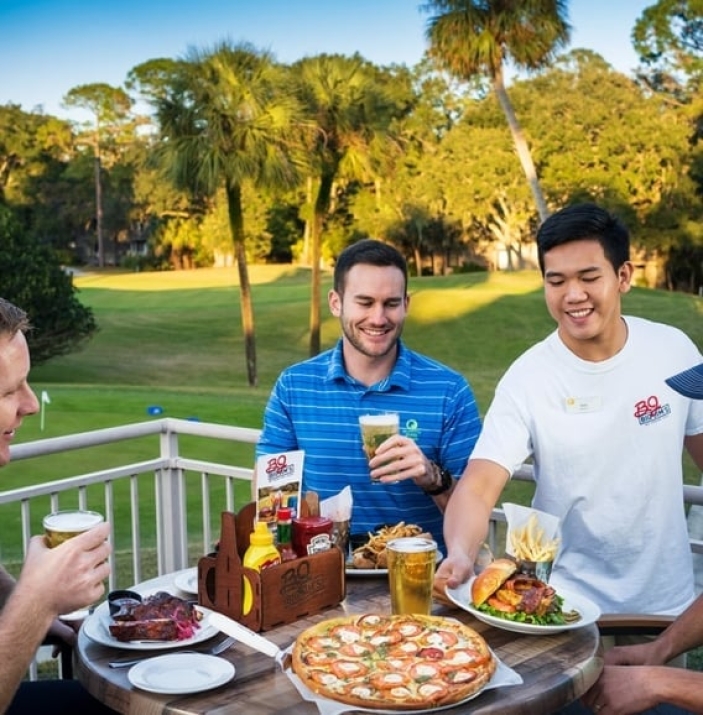 Big Jim's server delivering food to a group of men enjoying a beer on the patio