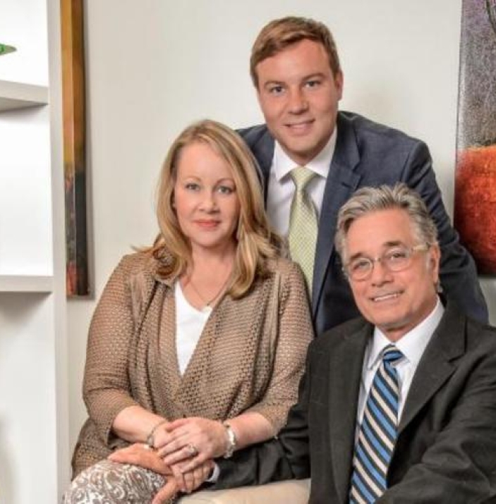 Three people in suits pose for the camera